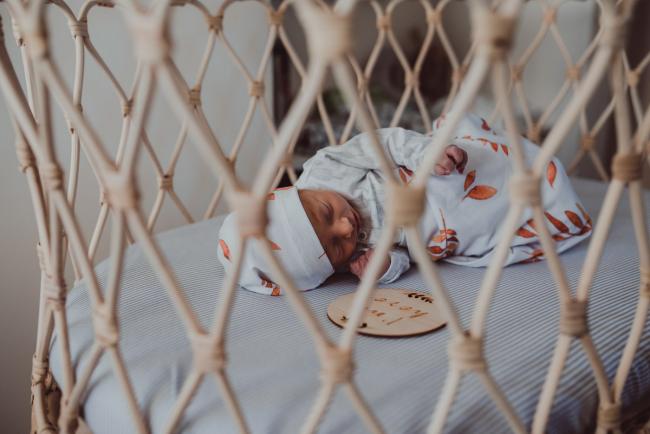 Looking at a new baby through the holes in a cane bassinet during a Perth Fresh 48 photography session captured in home