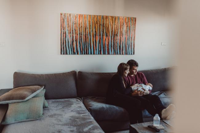 Parents smiling at their baby on the couch during a Perth Fresh 48 photography session captured in home