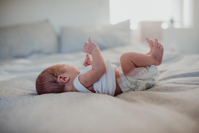 Side view of baby on a bed during a Perth Fresh 48 photography session captured in home