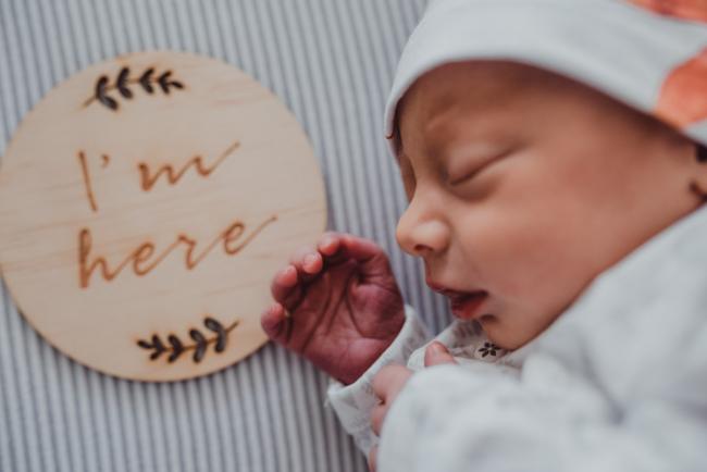 Close up of new baby next to an 'I'm here' wooden sign during a Perth Fresh 48 photography session captured in home