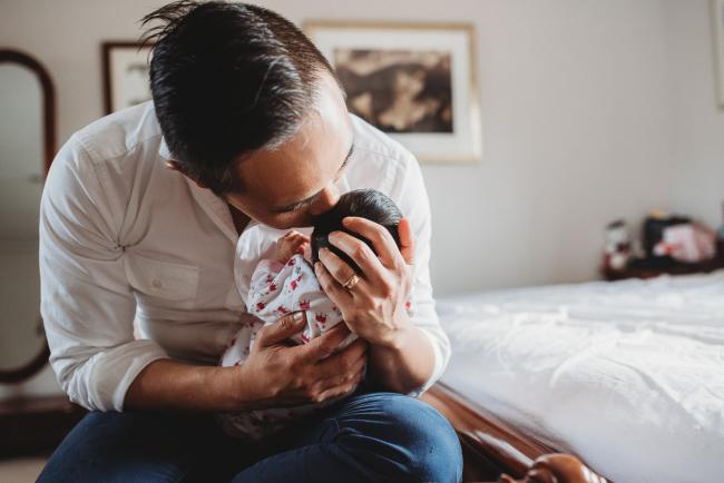 Father kissing his new baby's head during an in-home Perth Newborn Lifestyle photography session