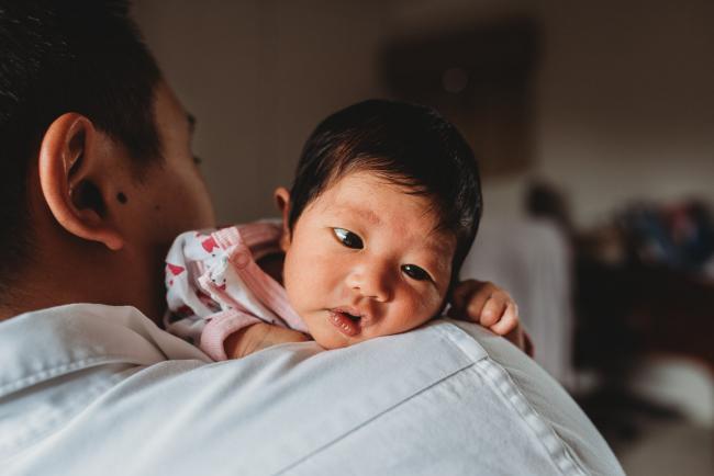 New baby's head over her father's shoulder during an in-home Perth Newborn Lifestyle photography session