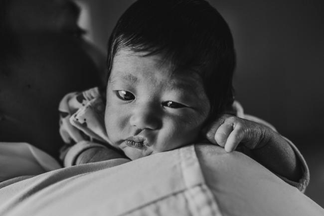 Black and white image of new baby's face squished against her father's shoulder during an in-home Perth Newborn Lifestyle photography session
