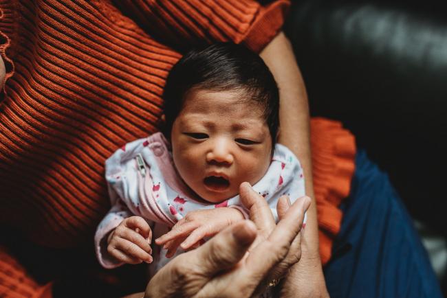 Grandmother touching the cheek of her new baby granddaughter during an in-home Perth Newborn Lifestyle photography session
