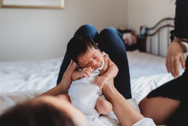 Father holding his new baby against his legs during an in-home Perth Newborn Lifestyle photography session