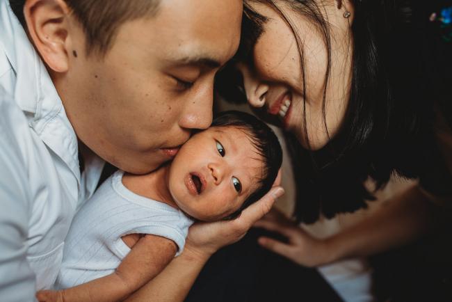 Parents kissing their new baby during an in-home Perth Newborn Lifestyle photography session