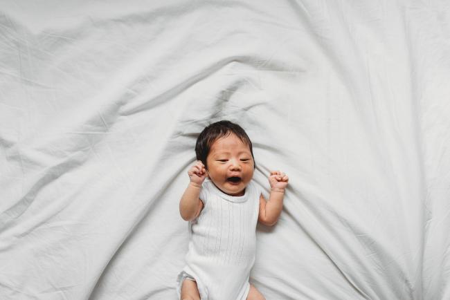 Top down image of baby laying on the bed during an in-home Perth Newborn Lifestyle photography session