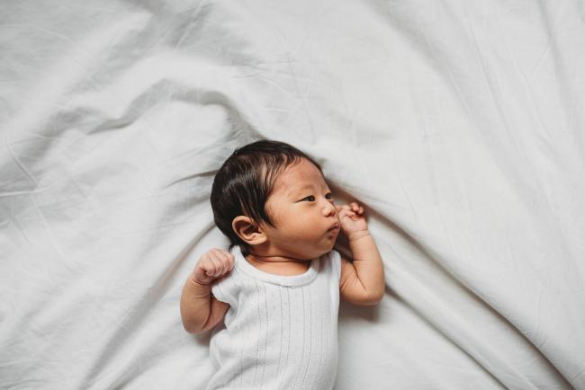 Top down image of new baby laying on the bed during an in-home Perth Newborn Lifestyle photography session