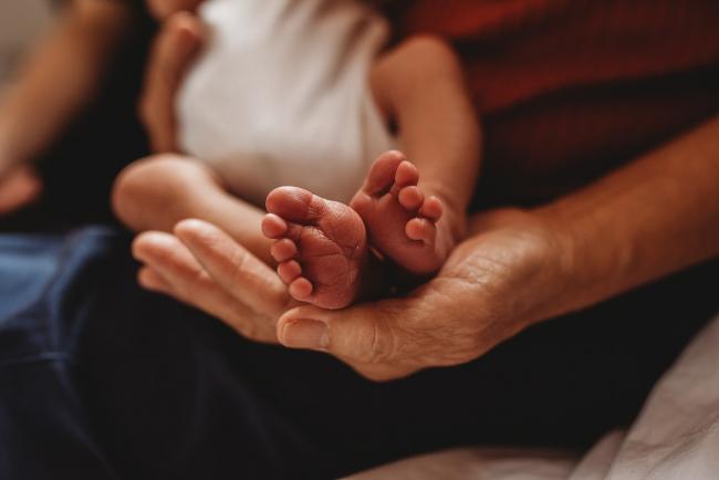 Grandmother holding the feet of her new baby granddaughter during an in-home Perth Newborn Lifestyle photography session