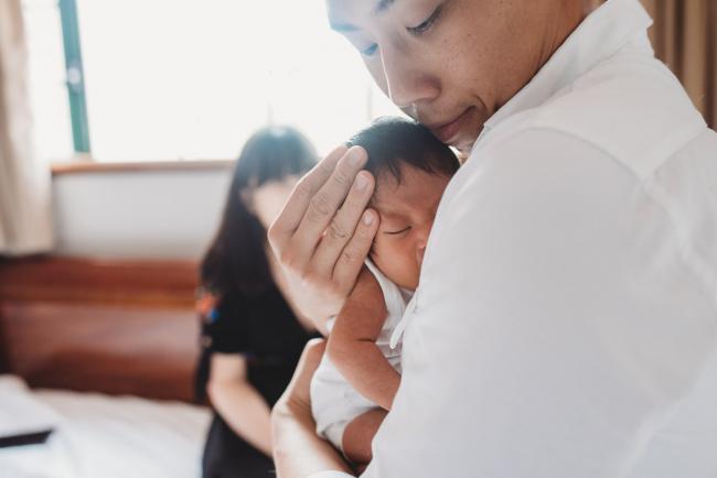 Father holding his new baby into his chest during an in-home Perth Newborn Lifestyle photography session