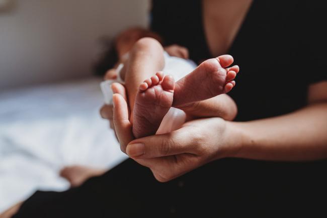 Mother holding new baby's feet in her hands during an in-home Perth Newborn Lifestyle photography session
