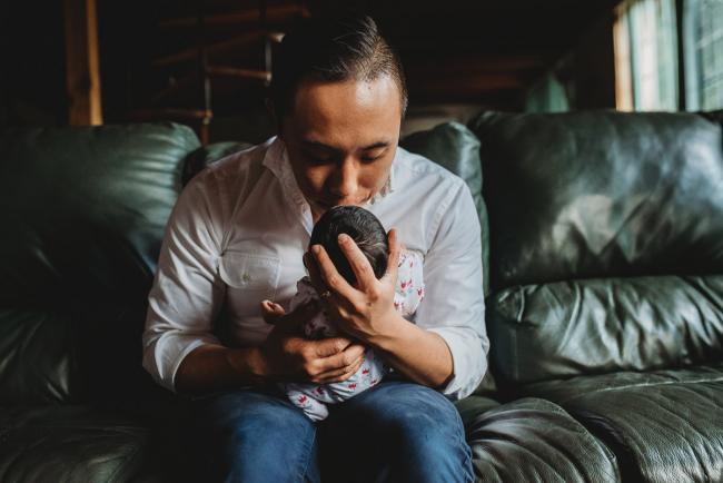 Father kissing the head of his new baby daughter during an in-home Perth Newborn Lifestyle photography session