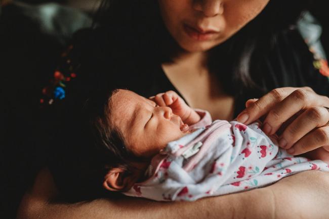 Close up of new baby daughter in mother's arms during an in-home Perth Newborn Lifestyle photography session