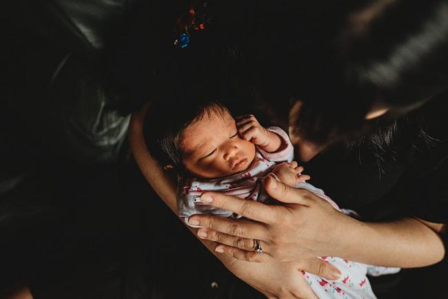 Top down image of new baby laying in her mother's arms during an in-home Perth Newborn Lifestyle photography session