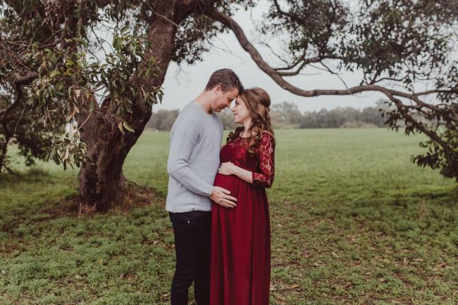 Pregnant couple under a tree with Perth maternity photographer at Perry's Paddock