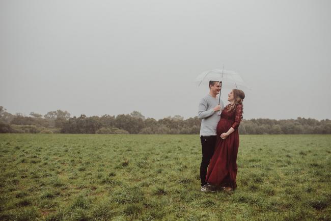Perth-Maternity-Photographer-Perrys-Paddock-12-of-39 Pregnant couple laughing under an umbrella during a Perth maternity session at Perry's Paddock during rain
