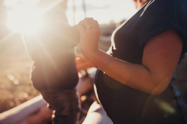 Pregnant woman holding son's hand with Perth maternity photographer at The Pines