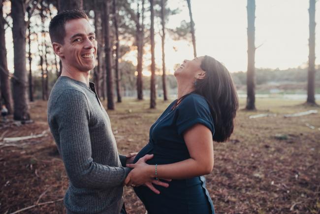 Pregnant couple laughing with Perth maternity photographer at The Pines