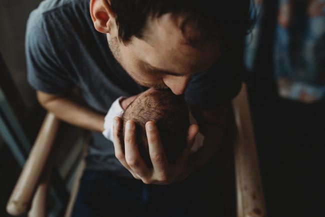 Father kissing his new baby's head during a Perth Fresh 48 photography session at SJOG Mt Lawley