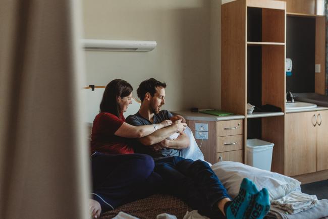 Parents holding their new baby on hospital bed during a Perth Fresh 48 photography session at SJOG Mt Lawley
