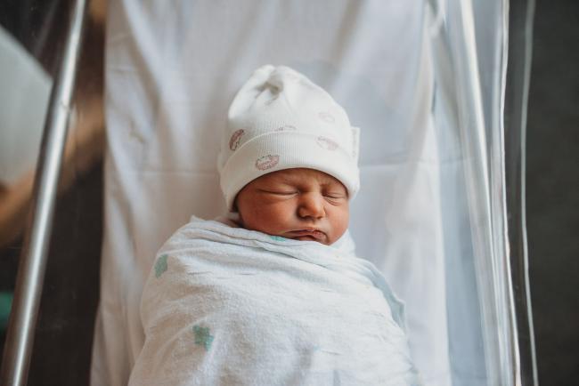 New baby in bassinet wearing a bonnet during a Perth Fresh 48 photography session at SJOG Mt Lawley