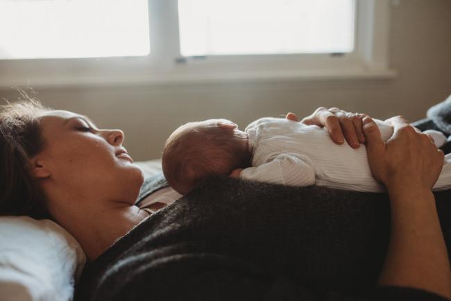 Mother laying with baby on her chest with lifestyle newborn photographer Perth