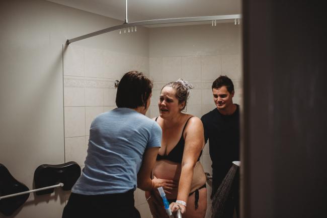 Pregnant woman with pained expression at the midwife during labour with Perth Birth Photographer at The Family Birthing Centre