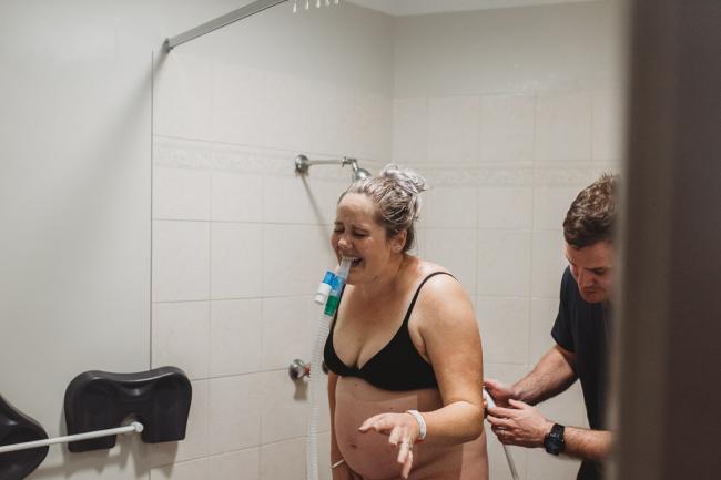 Pregnant woman using gas during labour as she stands in the shower with Perth Birth Photographer at The Family Birthing Centre