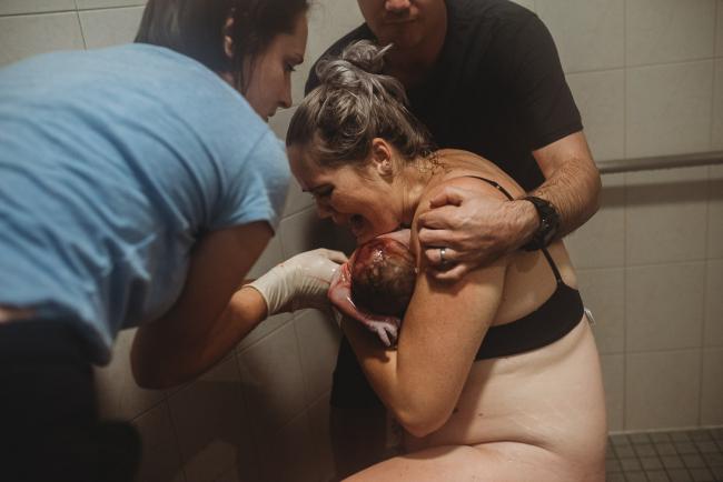 Mother holding her baby who has just been born in the shower with Perth Birth Photographer at The Family Birthing Centre