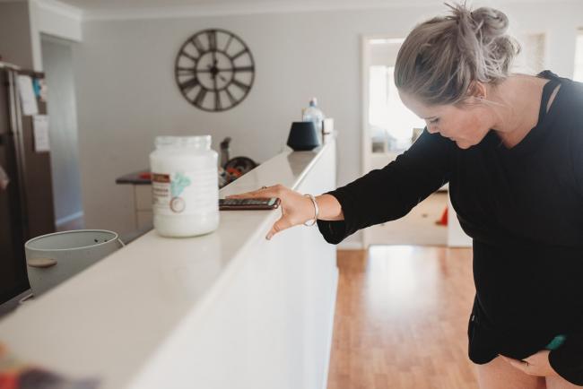 Pregnant woman leaning on her kitchen bench during a contraction with Perth Birth Photographer