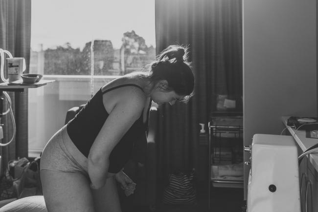 Birth-Photographer-Perth-17-of-60 black and white image of pregnant woman leaning over during contraction with Perth Birth Photographer at SJOG Mt Lawley