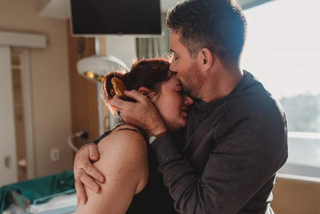 Birth-Photographer-Perth-20-of-60 Man cuddling and kissing his partner who is in labour with Perth Birth Photographer at SJOG Mt Lawley