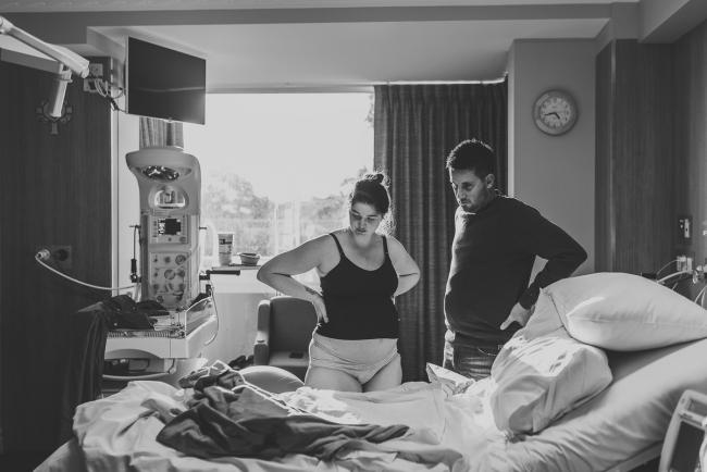 Black and white image of pregnant woman and partner standing with hands on their hips with Perth Birth Photographer at SJOG Mt Lawley