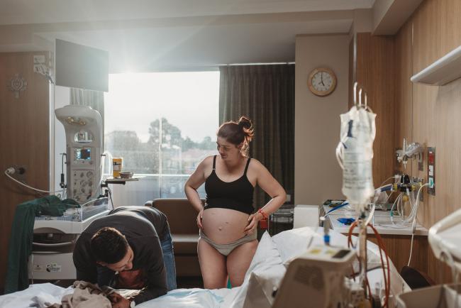 Birth-Photographer-Perth-28-of-60 Man leaning over the bed next to her pregnant partner with Perth Birth Photographer at SJOG Mt Lawley