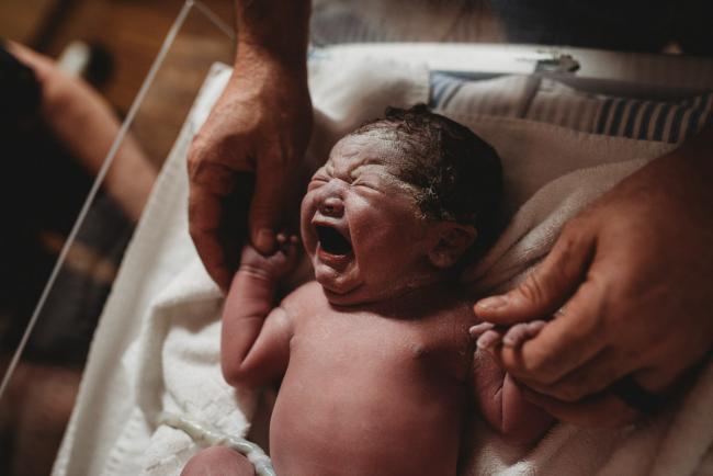 Birth-Photographer-Perth-60-of-60 Father holding hands of his newborn baby in bassinet with Perth Birth Photographer at SJOG Mt Lawley