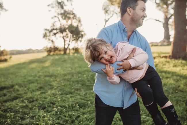 Uncle holding niece who is laughing during Perth family photography session at Perry's Paddock during golden hour