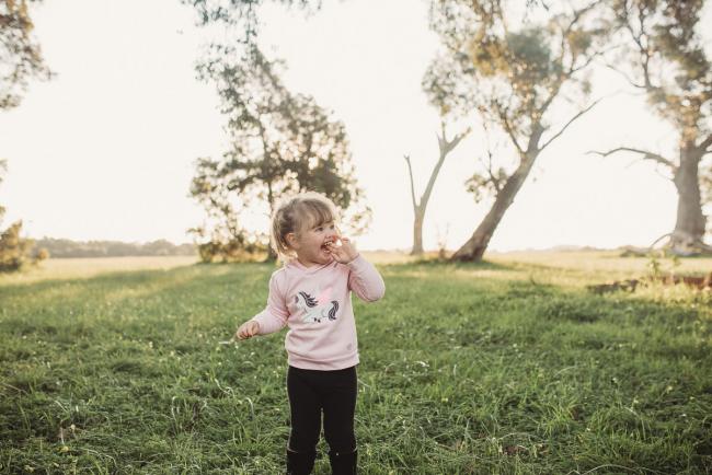 Little girl on grass during Perth family photography session at Perry's Paddock during golden hour
