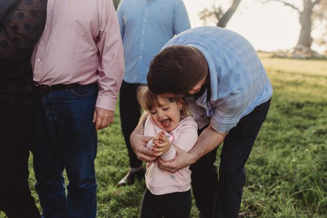 Father hugging daughter who is laughing during Perth family photography session at Perry's Paddock during golden hour