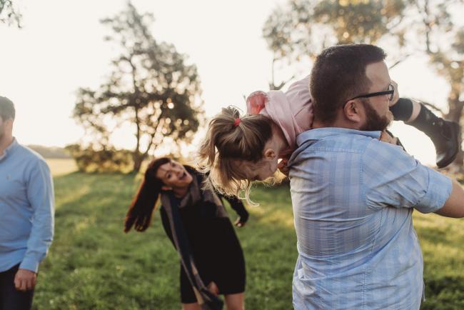 Father throwing daughter over his shoulder as woman laughs during Perth family photography session at Perry's Paddock during golden hour