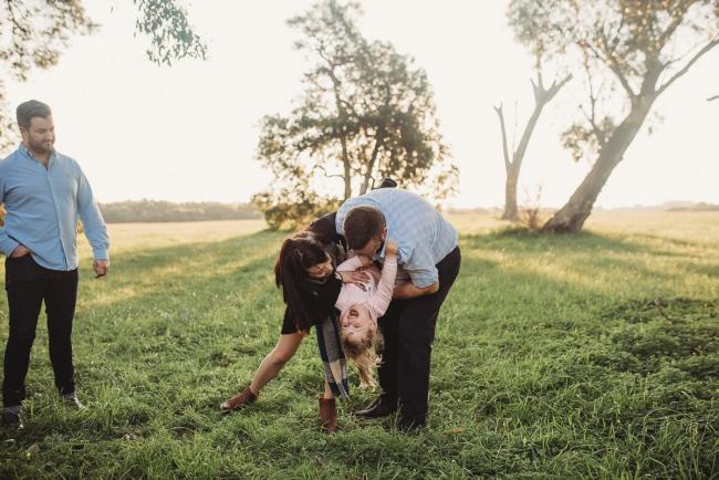 Man and woman tipping little girl upside down during Perth family photography session at Perry's Paddock during golden hour
