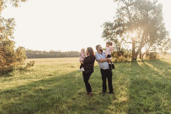 Parents holding daughters during Perth family photography session at Perry's Paddock during golden hour