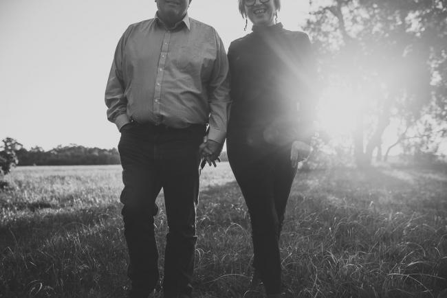 black and white image of man and woman walking hand in hand during Perth couples photography session at Perry's Paddock during golden hour