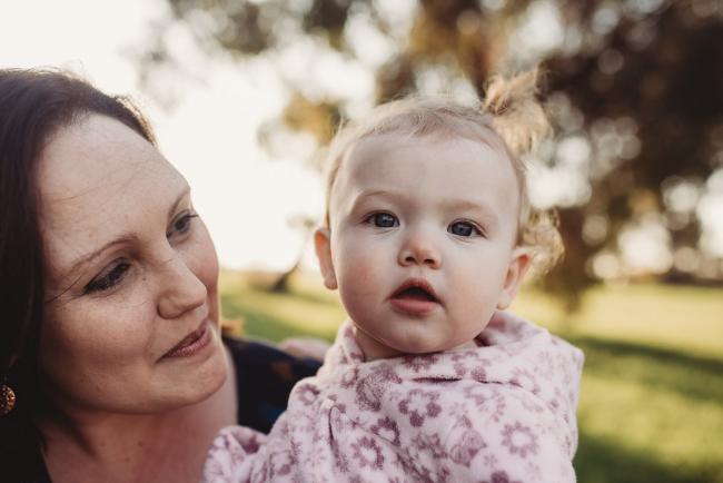 Mother smiling at daughter who is looking at the camera during Perth family photography session at Perry's Paddock during golden hour