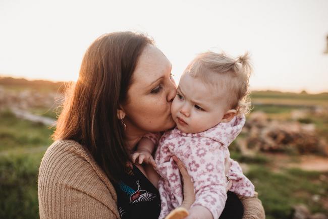 Mother kissing daughter during Perth family photography session at Perry's Paddock during golden hour