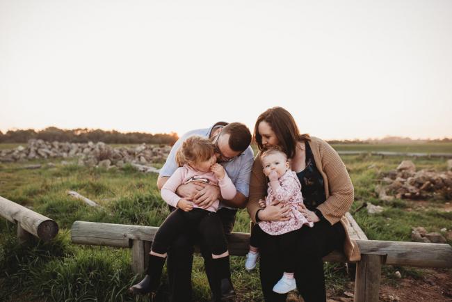 Family sitting on log during Perth family photography session at Perry's Paddock during golden hour