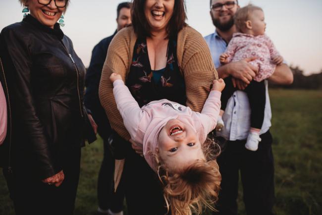Mother tipping daughter upside down during Perth family photography session at Perry's Paddock during golden hour