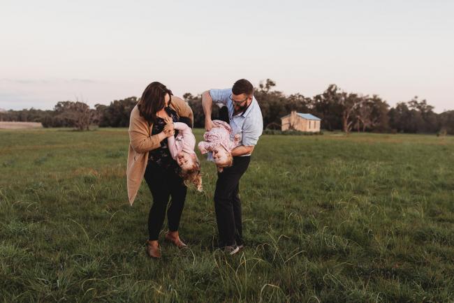 Parents tipping daughters upside down during Perth family photography session at Perry's Paddock during golden hour