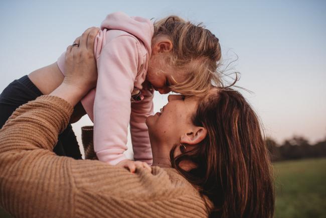 Mother lifting daughter above her during Perth family photography session at Perry's Paddock during golden hour