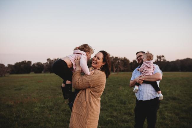 Parents holding daughters during Perth family photography session at Perry's Paddock during golden hour