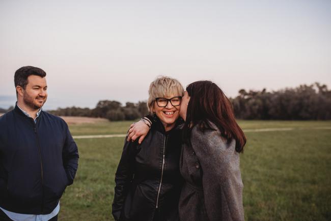 Woman kissing stepmother during Perth family photography session at Perry's Paddock during golden hour